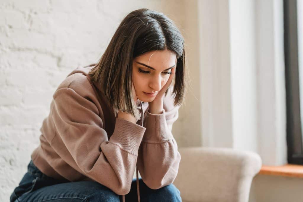 Una mujer más joven y cansada sentada en el sofá.