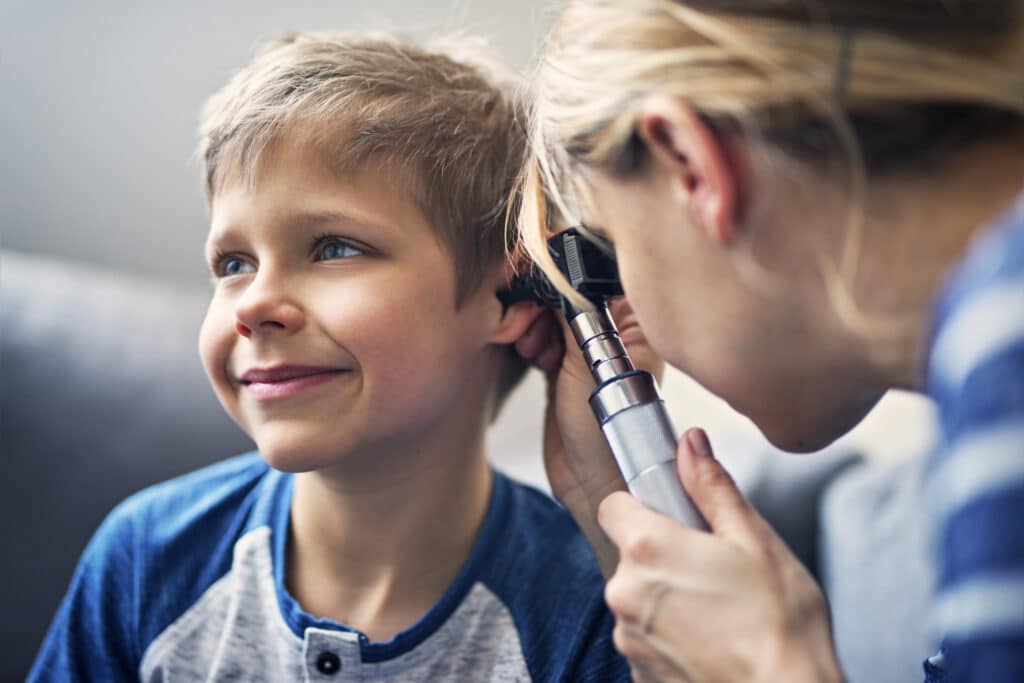 Un niño al que un médico le examina los oídos.