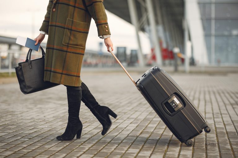 Mujer de moda que lleva su bolso al aeropuerto.